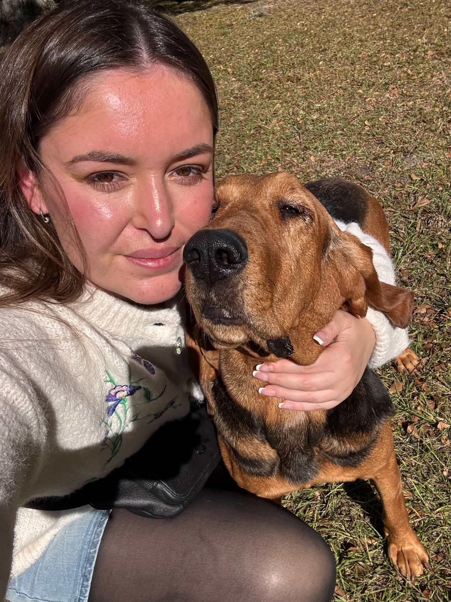 Alexis hugging a bloodhound in the grass